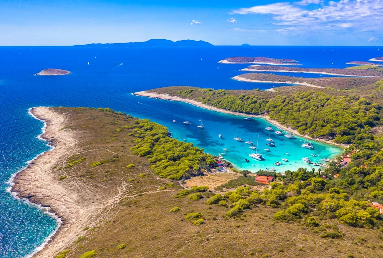 Aerial of a yacht-filled turquoise anchorage in the Pakleni islands archipelago