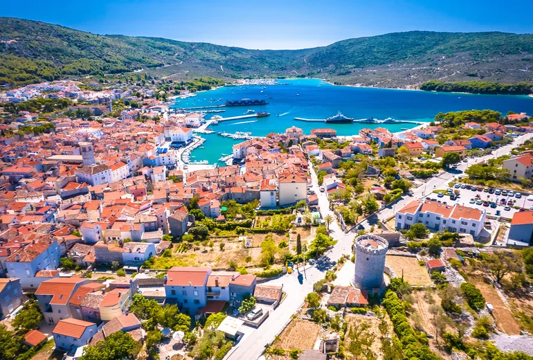 Aerial of Cres town red rooftops and round tower above its deep Venetian harbour bay