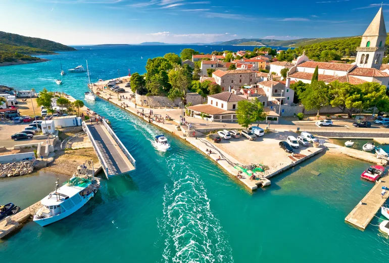Aerial of the Osor canal and swing bridge with a motorboat passing through town