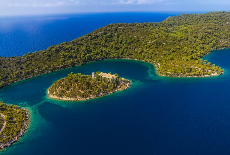 Aerial of the Saint Mary monastery islet in a forested Mljet national park lake