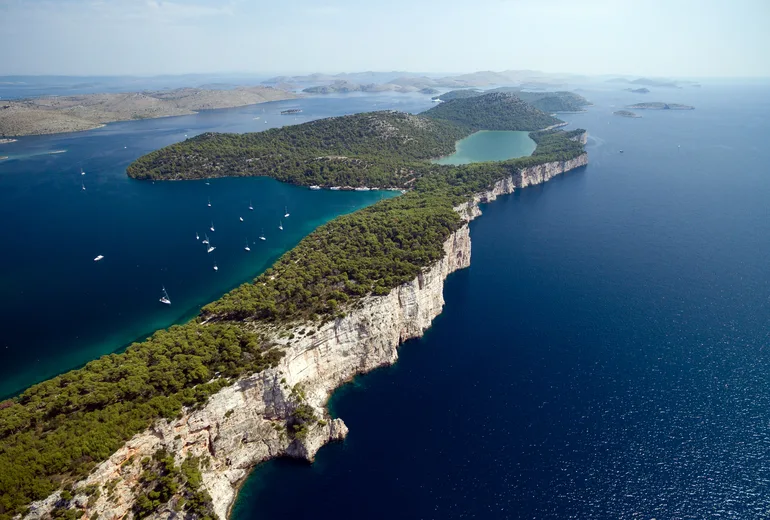 Aerial of the Telašćica cliffs, the inland salt lake Mir and anchored sailboats on Dugi Otok