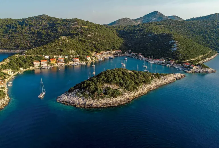 Aerial of Zaklopatica bay on Lastovo with an islet, village and moored sailboats