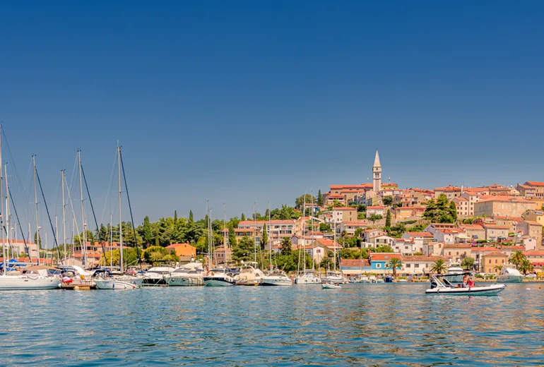 Hilltop coastal town with a bell tower above a marina full of sailboats