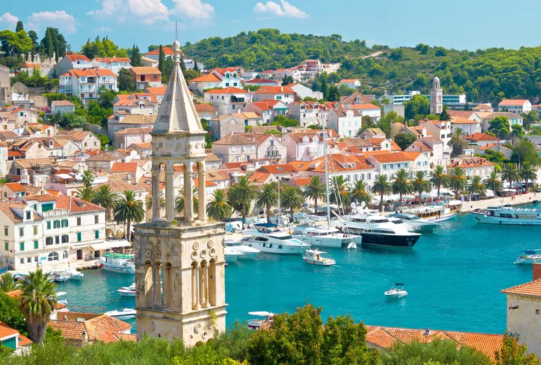 Hvar town bell tower, palm-lined waterfront and harbor viewed from above