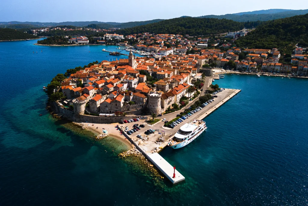 Aerial of Korcula walled old town peninsula with harbor and pier