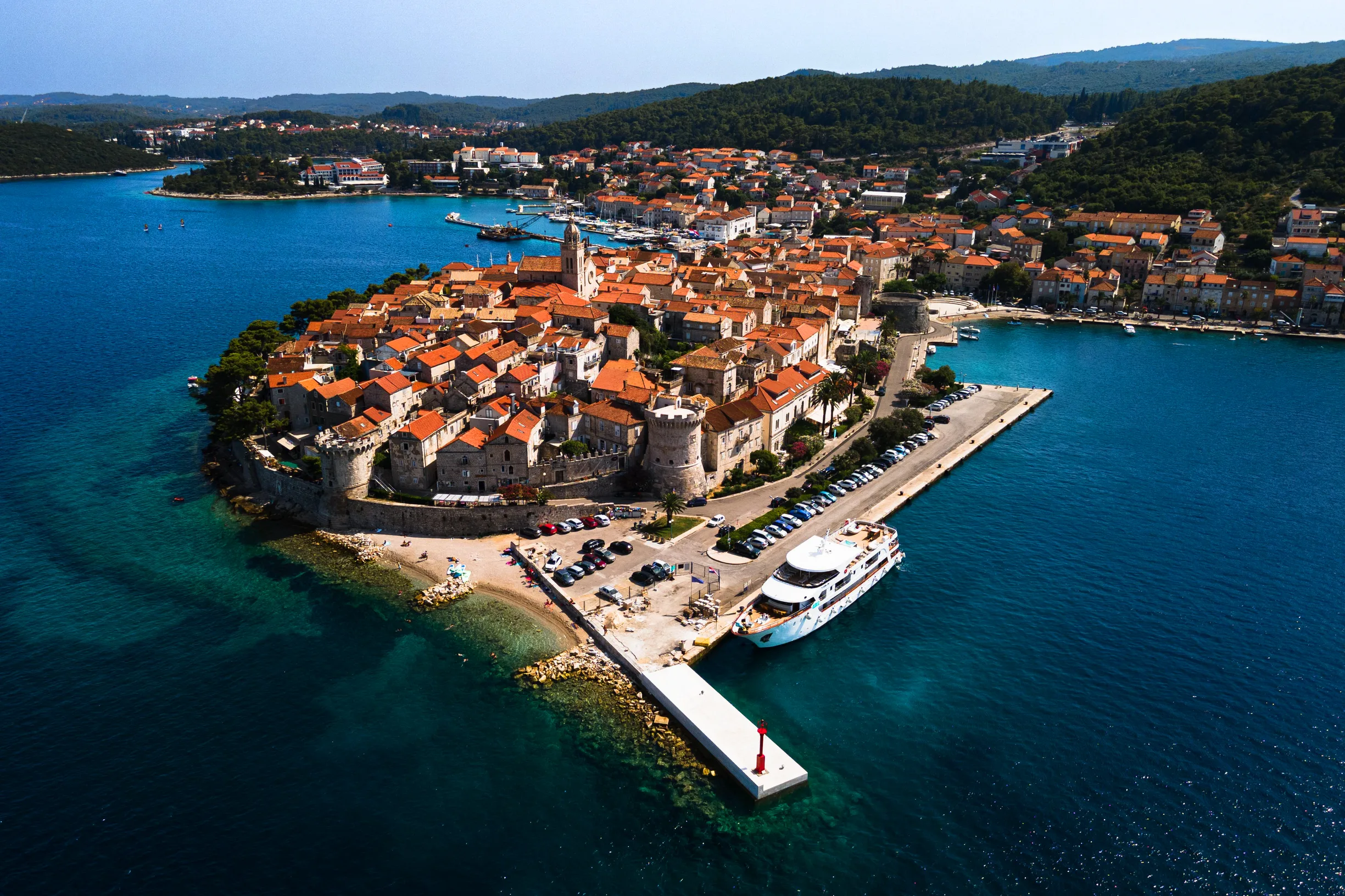 Aerial of Korcula walled old town peninsula with harbor and pier