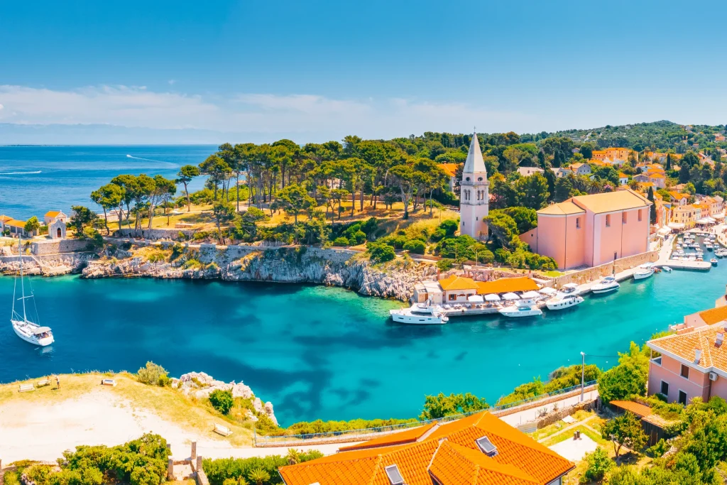 Veli Losinj village with bell tower, pastel houses and yacht-dotted cove