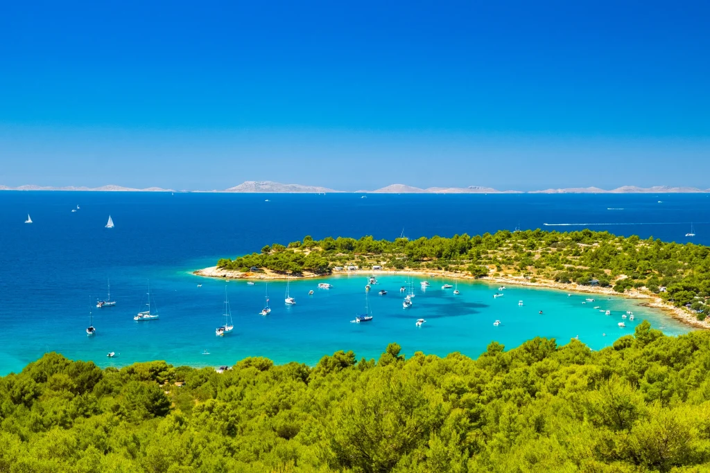 Turquoise bay anchorage with yachts, pine shores and distant islands