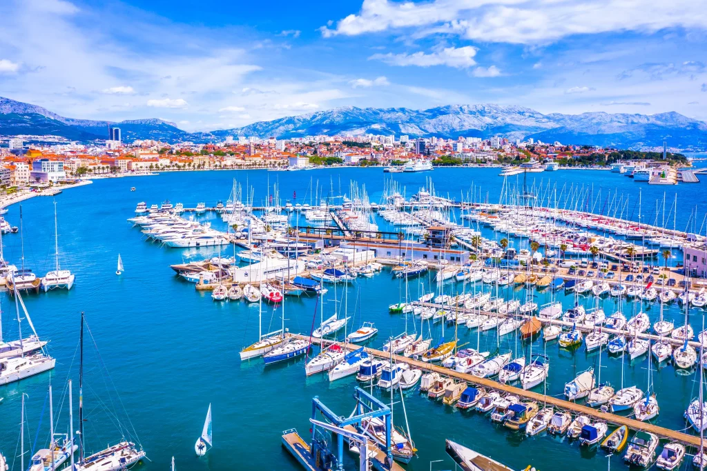 Split city marina packed with sailboats, mountains rising behind